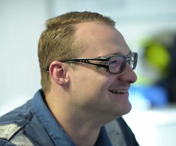 Standbild aus dem Employer-Branding-Video: ein lachender Mitarbeiter mit Schutzbrille im Interview